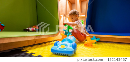Little toddler exploring bright activity toys in a fun and safe playroom with shelves and creative spaces Little toddler exploring bright activity toys in a fun and safe playroom with shelves and creative spaces 122143467