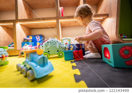 Little child exploring building blocks and educational toys in a cheerful learning area 122143499