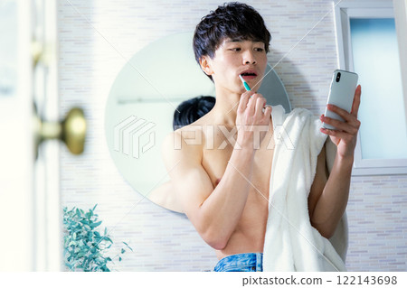 Young man brushing his teeth, smartphone 122143698