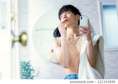 Young man brushing his teeth, smartphone 122143699