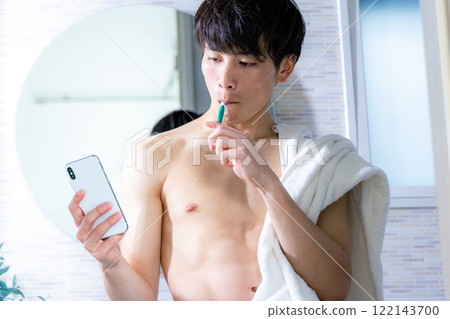 Young man brushing his teeth, smartphone 122143700