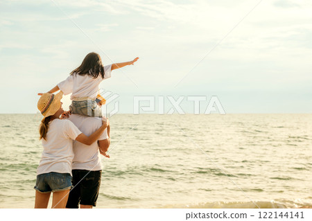Happy family in holiday. Father, Mother and kids having fun together shoulder ride on summer beach, Parents carrying children on neck at beach, family is enjoying their summer time Happy family in holiday. Father, Mother and kids having fun together shoulder ride on summer beach, Parents carrying children on neck at beach, family is enjoying their summer time 122144141