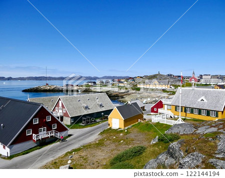 Picturesque cityscape of the historic center of the Arctic city Nuuk with brightly colored houses, a red church in the distance and blue waters of the fjord on a clear sunny summer day in Greenland 122144194
