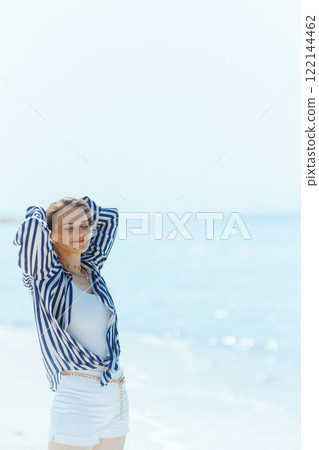 relaxed stylish woman on ocean shore enjoying tranquility 122144462