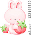 A little pink bunny is sitting hugging a strawberry. 122144529