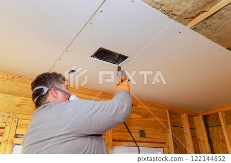 Contractor worker uses saw tool to install ventilation duct while renovating home interior. Contractor worker uses saw tool to install ventilation duct while renovating home interior. 122144852