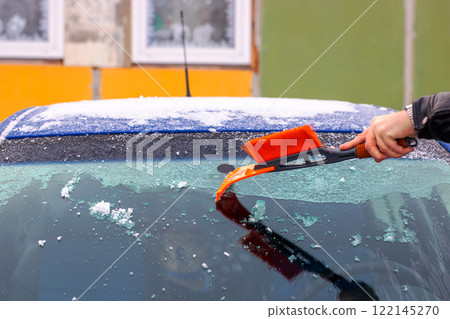 A person is cleaning the cars windshield with a brush A person is cleaning the cars windshield with a brush 122145270
