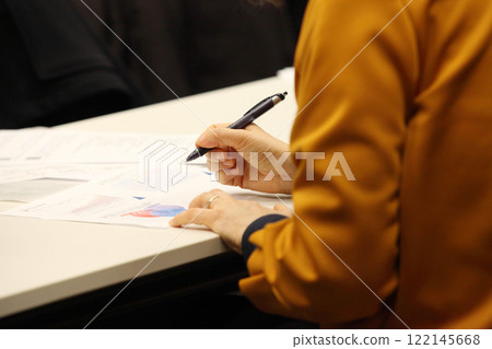 A woman's hand holding a pen and taking notes on a document A woman's hand holding a pen and taking notes on a document 122145668
