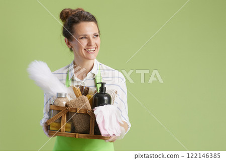 happy woman in green apron and rubber gloves against green 122146385