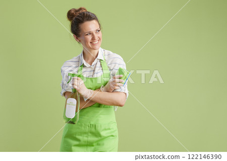 happy woman in green apron and rubber gloves against green 122146390