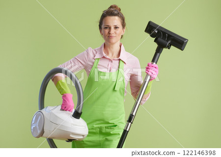 smiling modern housewife vacuum cleaner isolated on green 122146398