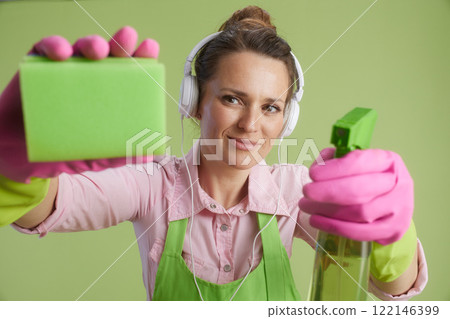 happy housewife in green apron and rubber gloves against green happy housewife in green apron and rubber gloves against green 122146399