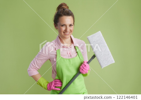 happy woman in green apron and rubber gloves against green 122146401