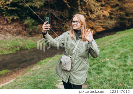 30s happy Woman uses a telephone for take pictures, make selfies and video calls friends on nature background. Travel and wanderlust concept. Amazing chill moment 30s happy Woman uses a telephone for take pictures, make selfies and video calls friends on nature background. Travel and wanderlust concept. Amazing chill moment 122147015