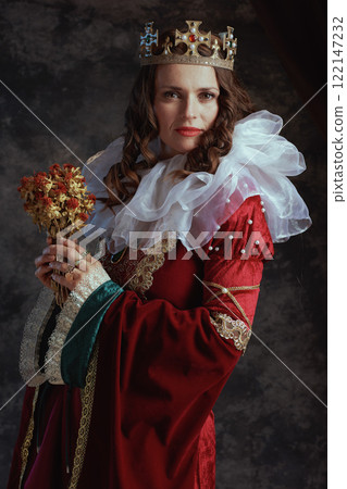 medieval queen in red dress with dried flower and white collar 122147232