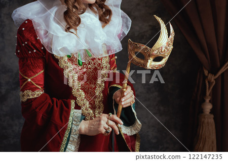 Closeup on medieval queen in red dress with venetian mask 122147235