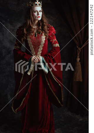 medieval queen in red dress with white makeup and crown 122147242