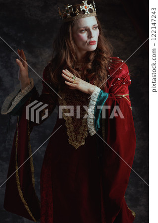 medieval queen in red dress with white makeup and crown 122147243