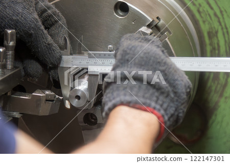Close up scene the lath machine operator measuring dimension of turning parts by Vernier caliper. 122147301