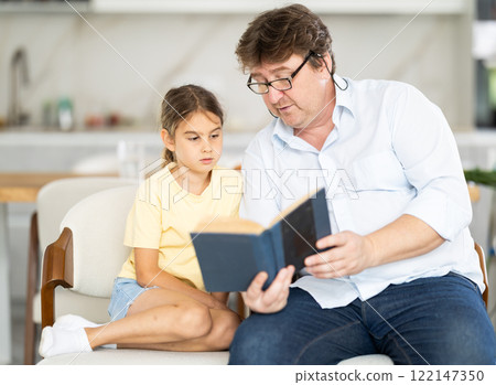 Father and daughter reading book together 122147350