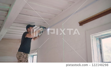 An electrician works with a drill to create electrical wiring. An electrician works with a drill to create electrical wiring. 122148298