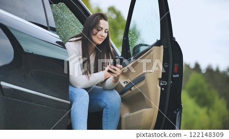 Professional working woman checking smartphone near open car door, utilizing mobile technology during travel break Professional working woman checking smartphone near open car door, utilizing mobile technology during travel break 122148309