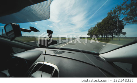 Dashboard camera capturing highway driving through windshield under bright sunlight 122148335