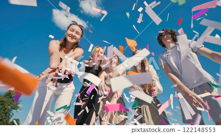Group of cheerful high school students throwing colorful confetti in the air, celebrating graduation or end of school year 122148553