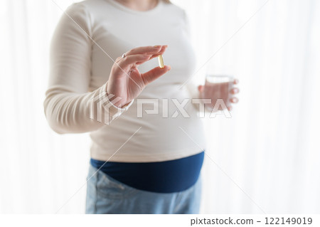 Pregnant woman holding a glass of water and taking vitamins and minerals during pregnancy. Pregnancy, health, pharmaceuticals, care. Close up Pregnant woman holding a glass of water and taking vitamins and minerals during pregnancy. Pregnancy, health, pharmaceuticals, care. Close up 122149019