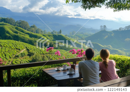 Couple Enjoying Tea On Balcony Overlooking Lush Green Hills. Bright Pink Flowers Add Color To Serene Landscape. Rolling Hills Stretching Into Distance Under Cloudy Sky. AI generated 122149143