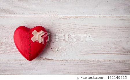 Broken Red Wooden Heart with Bandage on White Wooden Background 122149315