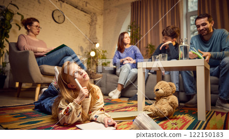 Focus on young girl, child lying on floor and drawing with thoughtful face, while her parents and teen brother talking with psychologist Focus on young girl, child lying on floor and drawing with thoughtful face, while her parents and teen brother talking with psychologist 122150183