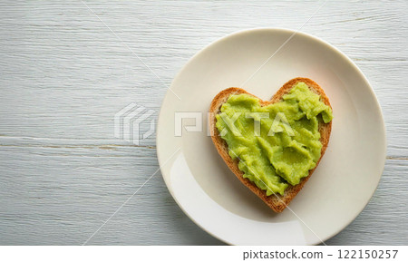 Heart Shaped Avocado Toast on White Plate with Wooden Background. Heart Shaped Avocado Toast on White Plate with Wooden Background. 122150257