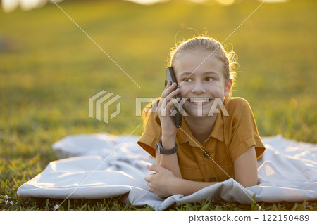 Child girl talking with her friend on cellphone outdoors in summer park Child girl talking with her friend on cellphone outdoors in summer park 122150489