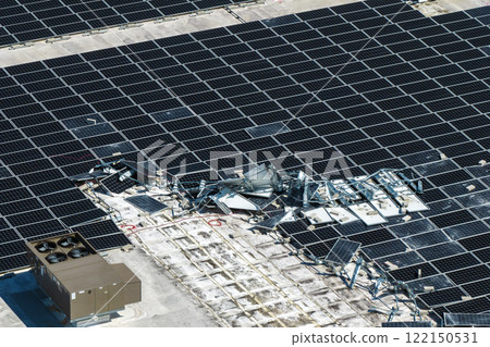 Broken down photovoltaic solar panels destroyed by hurricane Ian winds mounted on industrial building roof for producing green ecological electricity. Consequences of natural disaster 122150531