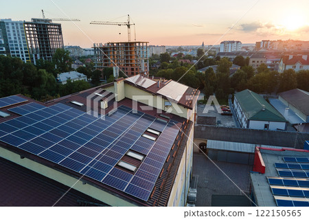 Blue photovoltaic solar panels mounted on building roof for producing clean ecological electricity at sunset. Production of renewable energy concept Blue photovoltaic solar panels mounted on building roof for producing clean ecological electricity at sunset. Production of renewable energy concept 122150565