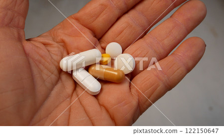 A woman's hand holds tablets on an open palm - round and in capsules. A woman's hand holds tablets on an open palm - round and in capsules. 122150647