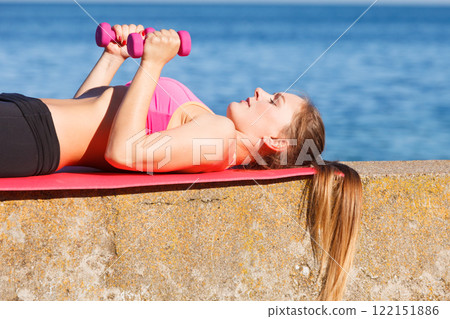 Woman doing sports outdoors with dumbbells 122151886