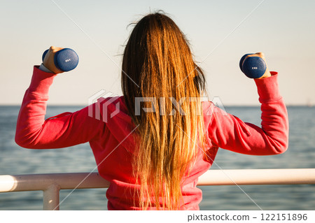 Woman doing sports outdoors with dumbbells Woman doing sports outdoors with dumbbells 122151896