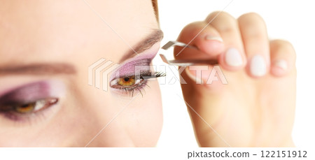 Woman tweezing eyebrows plucking with tweezers Woman tweezing eyebrows plucking with tweezers 122151912
