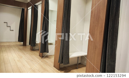 Empty changing rooms with wooden doors and white walls. Dressing rooms of a clothing store with no people. Shopping concept. Empty changing rooms with wooden doors and white walls. Dressing rooms of a clothing store with no people. Shopping concept. 122153294
