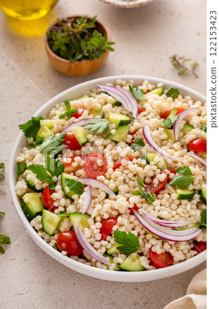 Pearl couscous salad with fresh vegetables and red onion 122153423