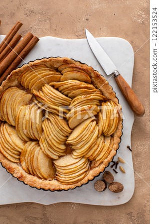 Apple pie or tart filled with sliced apples arranged on a pie base Apple pie or tart filled with sliced apples arranged on a pie base 122153524