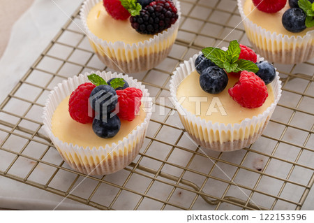 Mini vanilla cheesecakes cooked in a muffin pan served with fresh berries 122153596