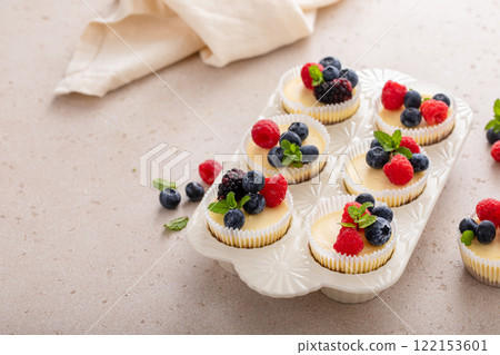 Mini vanilla cheesecakes cooked in a muffin pan served with fresh berries 122153601