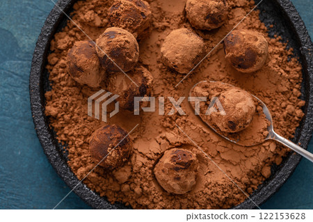 Artisanal chocolate truffles dusted with cocoa powder on a plate with a spoon 122153628