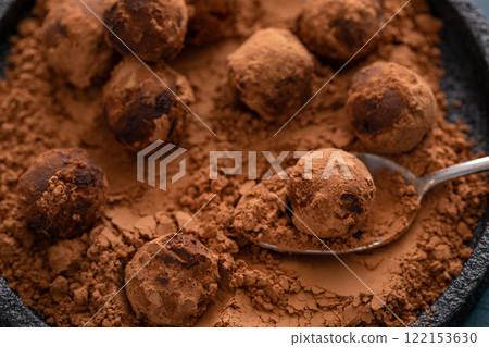 Artisanal chocolate truffles dusted with cocoa powder on a plate with a spoon 122153630