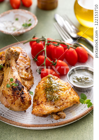 Roasted chicken drumsticks and thighs with pesto and tomatoes 122153710