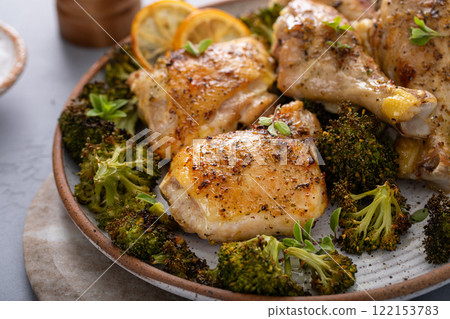Chicken drumsticks and thighs with broccoli roasted on a serving plate for dinner or lunch 122153783