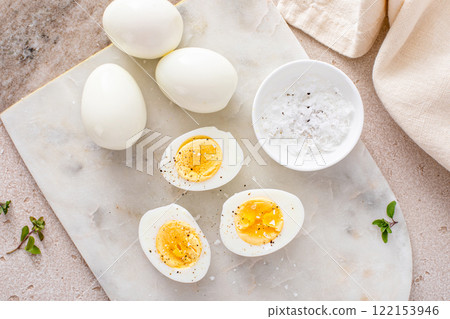 Boiled eggs peeled and cut in half with salt and pepper 122153946